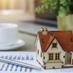 Casa en miniatura sobre gráficos de mercado, simbolizando la valoración de una vivienda heredada en Gran Canaria