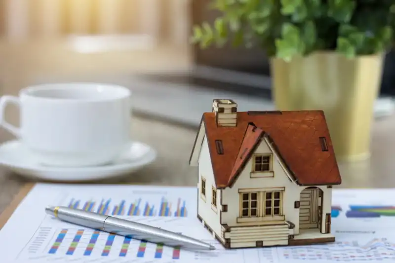 Casa en miniatura sobre gráficos de mercado, simbolizando la valoración de una vivienda heredada en Gran Canaria